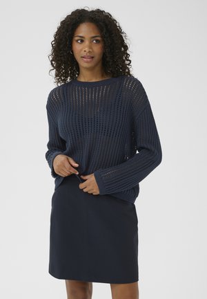 Pull en tricot bleu marine avec de larges rayures verticales, manches longues et coupe décontractée ; associé à une mini jupe bleu marine, texture lisse.