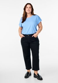 Svetlomodré tričko s vyhrnutými rukávmi skombinované s čiernymi nohavicami s vysokým pásom a mohutnými čiernymi mokasínami. Jednoduchý, neformálny outfit.
