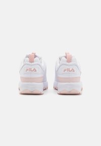 White athletic shoes with a textured upper, pink accents, and pull tabs. The sole is chunky and features a contrasting pink outsole design.