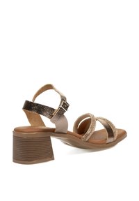 Sandalias de tacón marrón con correas metálicas doradas y plateadas, acentos texturizados, hebilla ajustable en el tobillo y un tacón bloque medio.