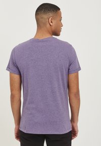 Lilla kortærmet t-shirt i et blødt, let stof med klassisk rund hals. Har rullede ærmekanter og en afslappet pasform.