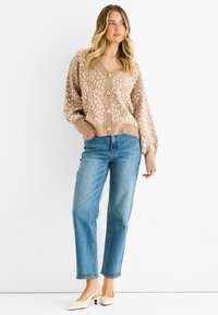 Beige cardigan with leopard print, v-neck, and wooden buttons; paired with light blue straight-leg jeans and cream heels.