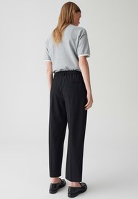 Grijs shirt met korte mouwen en witte rand gecombineerd met zwarte broek met elastische taille, met een gladde textuur en een enkele achterzak.
