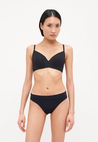 Black seamless bra with adjustable straps and scalloped edges, paired with matching black low-rise panties, smooth texture, minimalistic design.