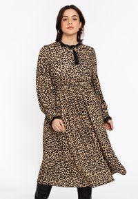 Beige Kleid mit schwarzem Leopardenmuster. Verfügt über einen gerafften Kragen und Ärmelabschlüsse, eine geraffte Taille und einen schwingenden mittellangen Rock.