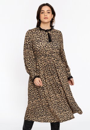 Robes à imprimé animal en beige avec des taches de léopard noires. Présente un col et des poignets volantés, une taille froncée et une jupe fluide de longueur mi-mollet.