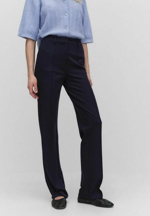 Marineblaue, taillierte Hose mit schmalem Bund, zwei seitlichen Taschen und einer glatten, strukturierten Oberfläche. Kombiniert mit einem hellblauen Strickoberteil.