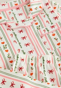 Weißes Pyjama-Set mit pinken und grünen Streifen, verziert mit Zuckerstangen, Schleifen, Herzen und festlichem Text. Detaillierter Kragen und Knopfverschluss.