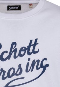 Felpa bianca con una grande scritta blu navy che recita "Schott bros inc.". L'etichetta interna indica la taglia L e include un'icona di bandiera.