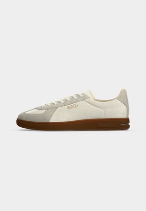 Λευκό και ανοιχτό γκρι χαμηλό sneaker με καφέ σόλα, κορδόνια μπροστά και λογότυπο "Polo" στη πλευρά.