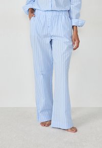 Pantalones de pijama a rayas azul claro con cintura elástica y bolsillos laterales, con un diseño de pierna ancha, hechos de una tela suave.