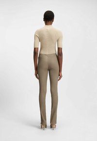 Beige knit top with short sleeves paired with fitted taupe pants. The outfit features a seamless design and sleek texture.