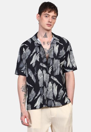 Camisa de manga corta en azul marino con patrones abstractos de olas blancas. Presenta un cuello y un corte relajado. La tela parece ligera y texturizada.