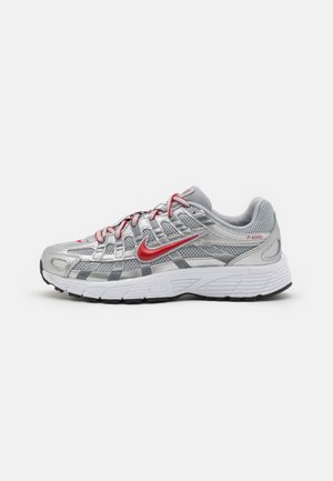 Baskets de course argentées avec tige en mesh, accents gris, détails rouges, virgule proéminente, et semelle blanche rembourrée avec traction noire.