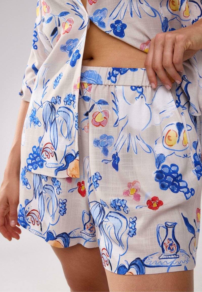 Blomster mønstrede linnedshorts med blå og lyserøde håndtegnede illustrationer, med elastisk talje og løs pasform.