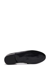 Schwarze Ledersohle mit glänzender Oberfläche, die ein strukturiertes Krokodilmuster und eine geschwungene Form für ein elegantes Erscheinungsbild aufweist.