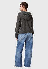 Kolgrå huvtröja med avslappnad passform, ribbad nederkant, kombinerad med ljusblå vida jeans med fransar i nederkant och bakfickor.