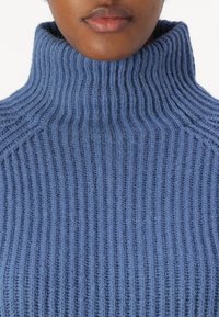 Hellesblaues, geripptes Rollkragensweatshirt aus weichem Strickmaterial mit hohem Kragen, vertikaler Textur und taillierter Passform.