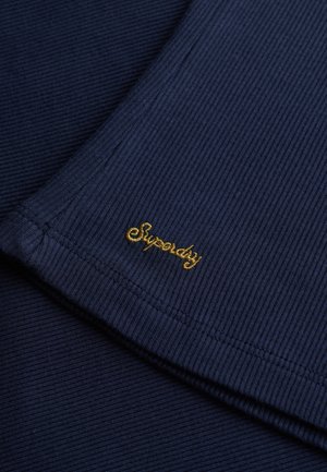 Granatowa, prążkowana tkanina z złotym haftem "Superdry". Charakteryzuje się gładką fakturą i starannie wykończonymi krawędziami.