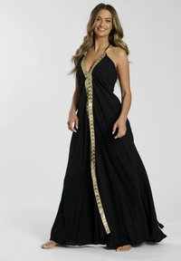 Vestido maxi negro con halter que presenta una silueta fluida, con un borde decorativo dorado en la parte delantera y flecos en el dobladillo.
