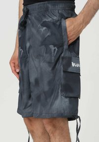 Pantaloni da bagno grigio scuro realizzati in materiale leggero e resistente all'acqua. Le caratteristiche includono una tasca laterale e una vita elastica con cordino.