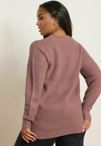 Pull en maille couleur rose poussiéreux, doté d'une texture côtelée, de manches longues et d'une coupe décontractée avec un col arrondi et des fentes sur les côtés.