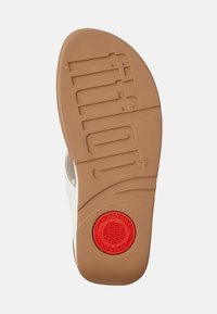 Sole di sandalo in gomma con una superficie marrone chiaro e texture. Accento circolare rosso notevole con scanalature, logo di marca e design sagomato.