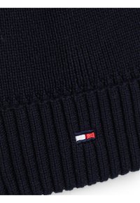 Marine gebreide muts met ribbeltextuur en een klein geborduurd logo met blauwe, witte en rode accenten nabij de onderkant.