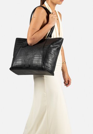 Borsa tote in pelle nera con stampa coccodrillo, dotata di doppio manico, chiusura con cerniera e dettaglio del marchio. Forma rettangolare con finitura testurizzata.