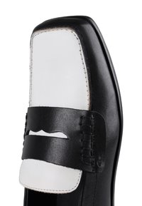 Zapato de cuero negro con un acento blanco en la punta, con forma cuadrada, bordes cosidos y un diseño de correa en contraste.