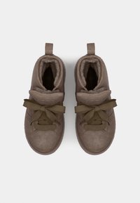 Brune semskede høye sneakers med myk fôr, flate olivengrønne snøringer og en løkke på baksiden for enkel påkledning.