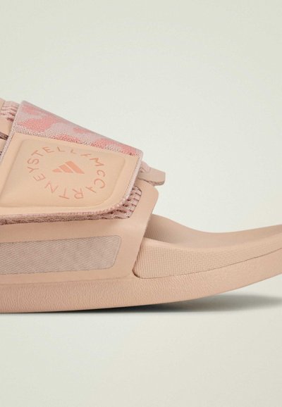 Sandale à glissière rose avec bride ajustable, semelle en caoutchouc souple, dessus texturé et détail du logo. Comprend un accent en maille pour la respirabilité.