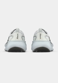 Λευκά και μαύρα αθλητικά παπούτσια με υφασμένο πέλμα, μαξιλαρωμένη φτέρνα και εμφανές λογότυπο στο πίσω μέρος, με ομαλό σχεδιασμό στο επάνω μέρος.