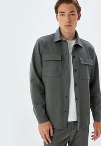 Kolenstofgrijze button-up overhemdjas met twee borstzakken, lange mouwen en een rechte zoom. Gemaakt van zachte, gestructureerde stof.