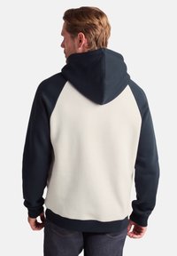 Hooded sweatshirt in navy and ivory, featuring a color-blocked design with a kangaroo pocket and ribbed cuffs. Soft fleece material.