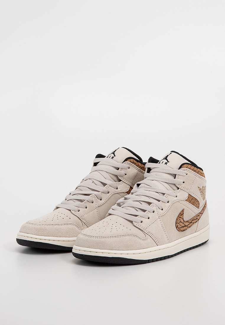 Las zapatillas altas de ante beige presentan un acento marrón texturizado y una suela negra. Incluyen punta redondeada y un diseño de cordones tradicional.