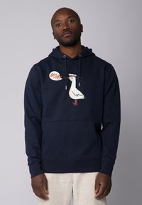 Navyblaues Sweatshirt mit einer vorderen Tasche, das ein weißes Möwenmotiv und den Text "MOIN!" in einer Sprechblase zeigt. Hergestellt aus weichem Stoff.