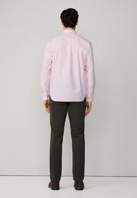 Camisa de cuadros rosa de manga larga con un cuello, combinada con pantalones verde oliva y zapatos marrones, vista desde la parte de atrás.