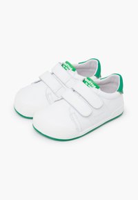 Zapatos blancos con una textura de cuero suave, con acentos verdes en el talón y la correa, equipados con cierres de velcro para una fácil puesta.