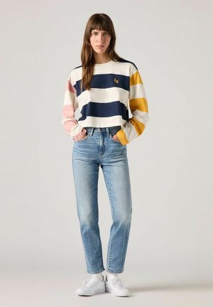 Camiseta de manga larga a rayas en crema, azul marino, rosa y amarillo. Combinada con jeans rectos de mezclilla en azul claro y zapatillas blancas. Presenta detalle de logo.