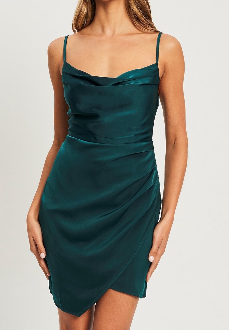 En teal satin klänning med en cowl neckline, tunna axelremmar och sidodrapering, med en figurnära silhuett och en något asymmetrisk nederkant.