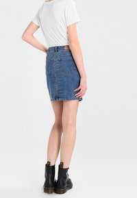 Jeanskjol med en figurnära design, längd till mitten av låret och två bakfickor. Matchad med en vit t-shirt och svarta ankelstövlar.