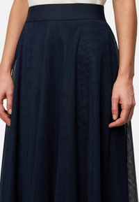 Jupe bleu marine en matériau superposé et transparent. Dotée d'une large taille élastique et d'une texture verticale subtile sur l'ensemble.