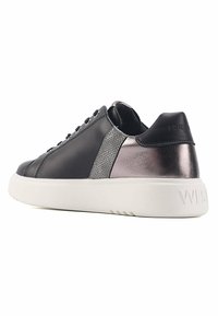 Zapatilla de cuero negro con un acento metálico gris, suela blanca y panel lateral texturizado. Presenta puntera redondeada y cierre con cordones.