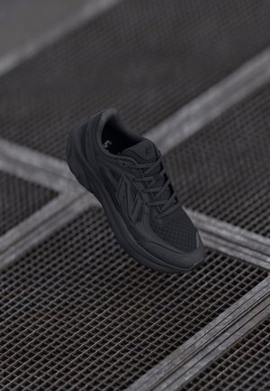 Adidași negri pentru alergare, cu plasă superioară, talpă texturată și design flexibil. Logo-ul 'N' proeminent pe lateral, șireturi și toc cu amortizare.