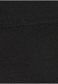 Black ribbed fabric featuring vertical lines and a smooth texture, with visible stitching and seams throughout the material.