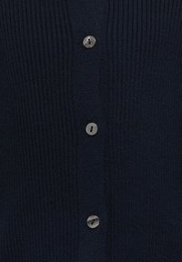 Tumši zils ribbet kardigans ar piecām sudraba pogām, raksturīgi ar teksturētu trikotāžu un klasisku piegriezumu. Piemērots kā slānis vēsākos laikapstākļos.