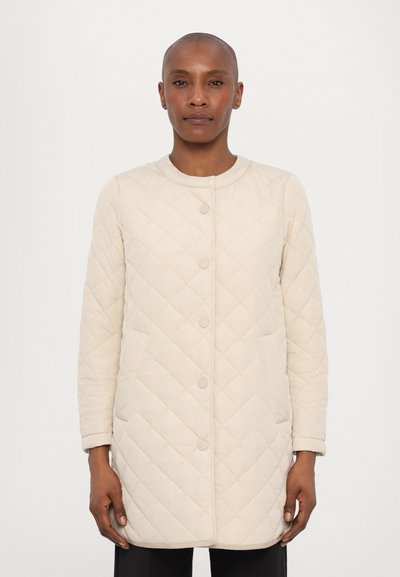 Quiltet beige jakke med rund halsudskæring, frontknapper og sidelommer. Stoffet har en blød, tekstureret overflade med en let glans.