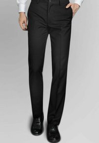 Pantalons noirs avec une coupe ajustée, présentant une texture lisse, un devant plat et des poches latérales. Associés à des chaussures noires brillantes.