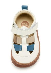 Zapato de cuero blanco con suela marrón, que presenta acentos en azul y beige, una correa en la parte superior y diseños troquelados para ventilación.